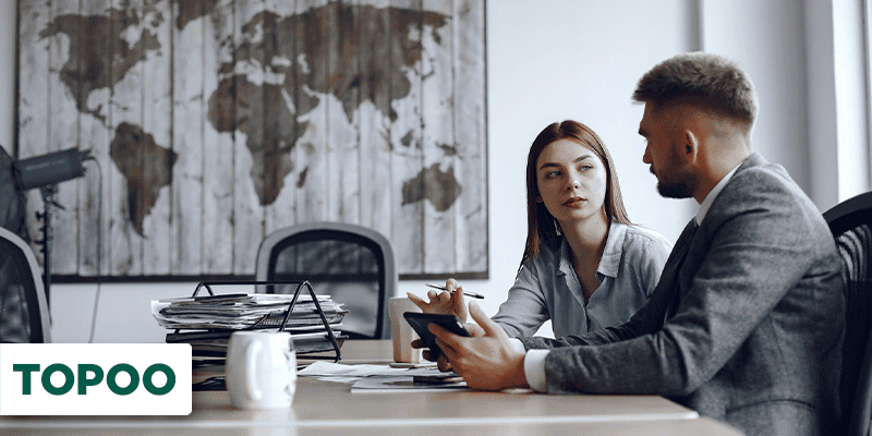 Duas pessoas em reunião empresarial em uma sala com mapa mundi ao fundo