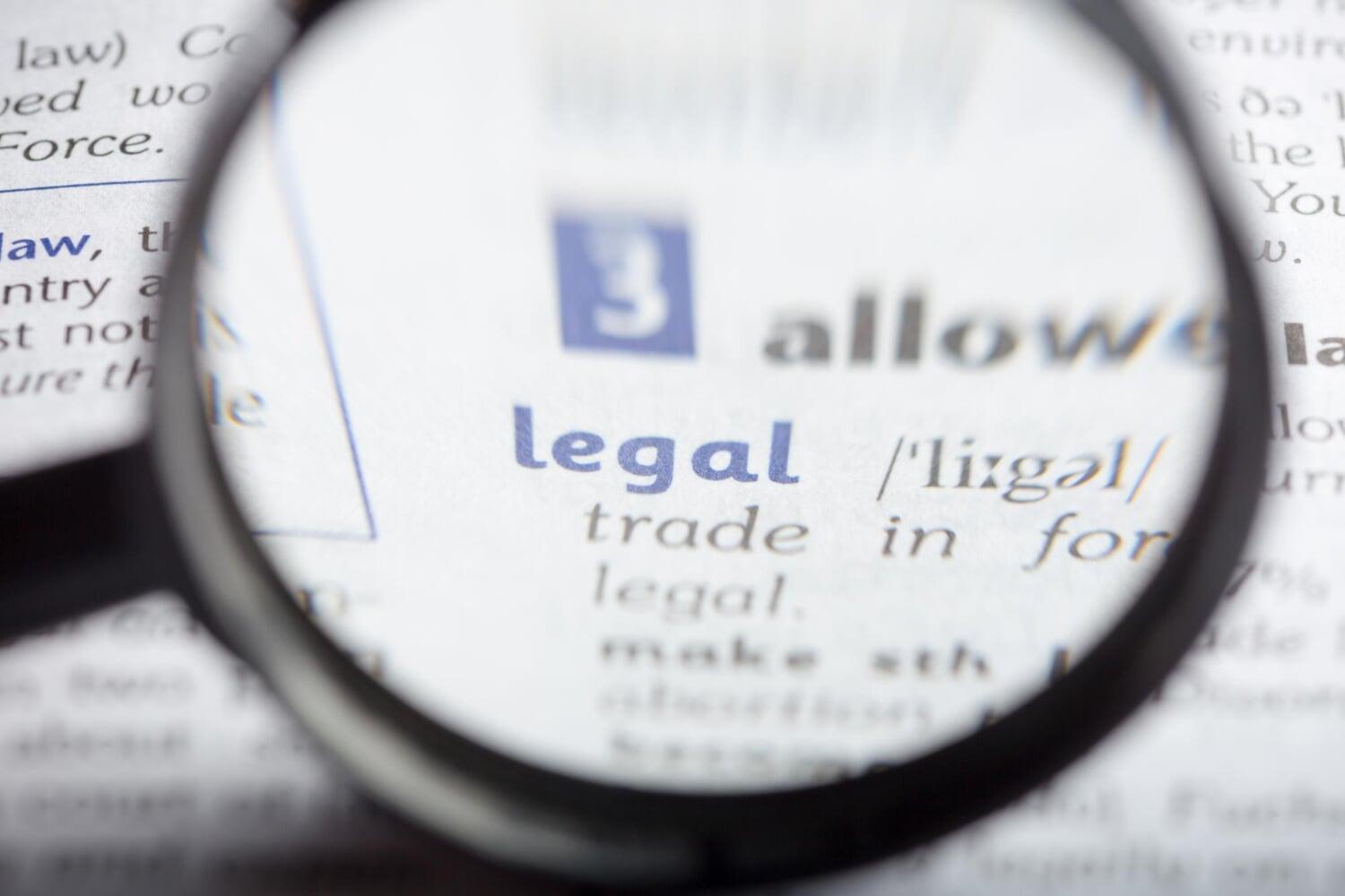 Foco na palavra legal em texto jurídico com lupa ampliando o termo