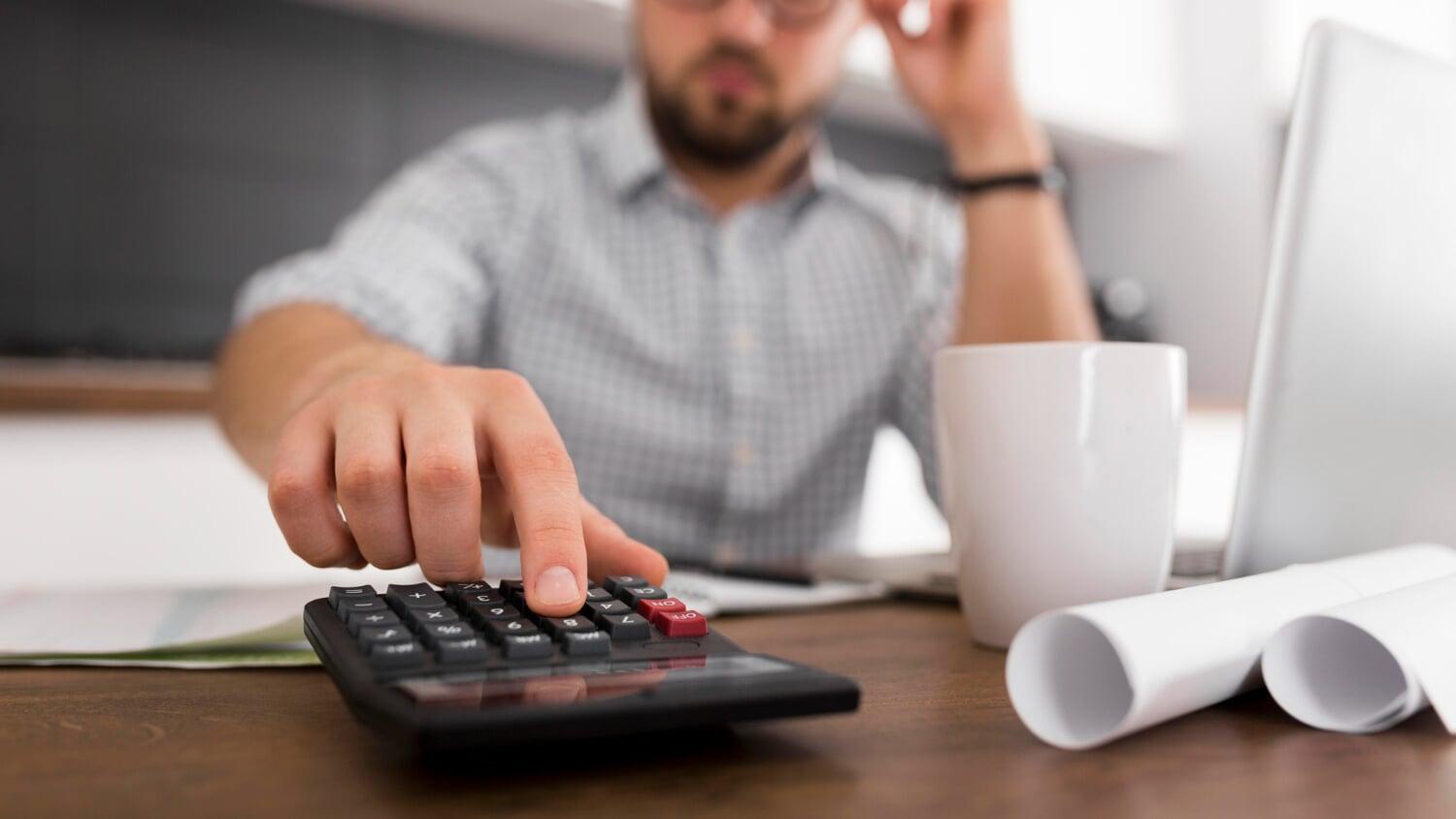 Empresário analisando opções de crédito com calculadora e documentos sobre a mesa