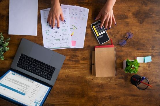 Mesa de trabalho com notebook, documentos fiscais, celular e planilhas de planejamento financeiro