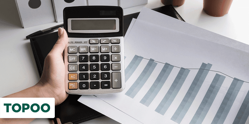 mão segurando calculadora com gráficos sobre a mesa